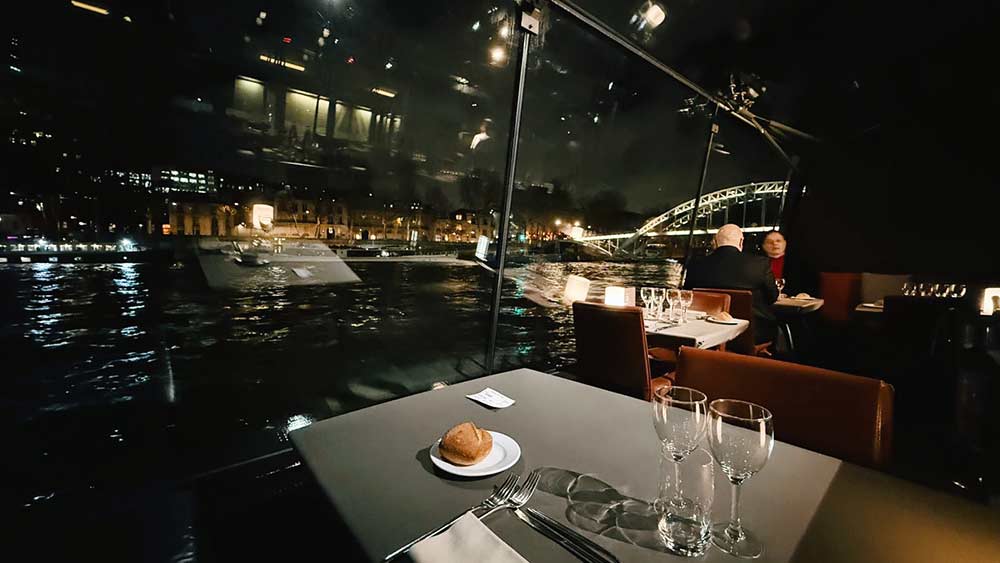 Cenar en el río Sena de París con la ciudad iluminada.